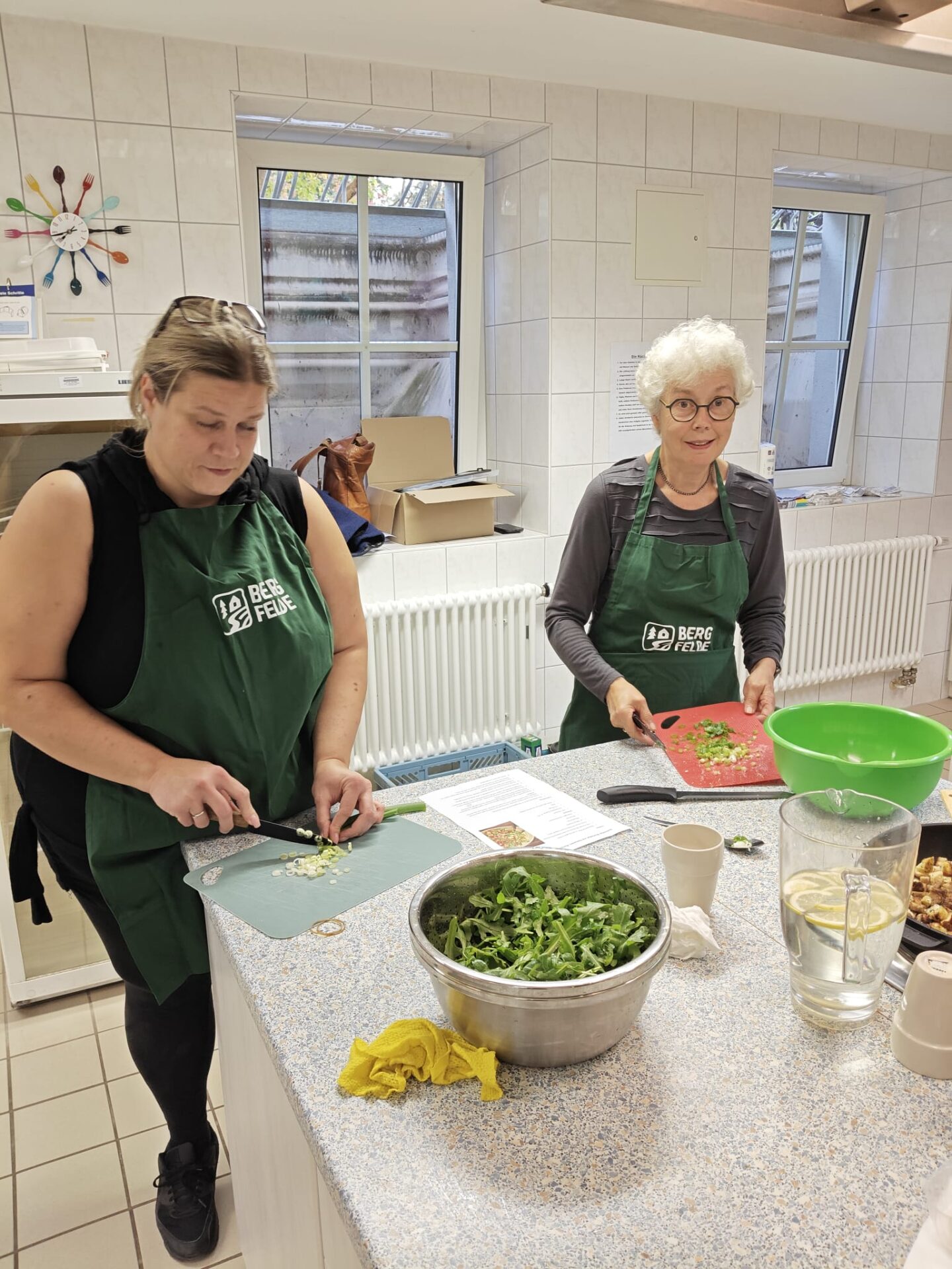 Alles nur Salat: zwei Teilnehmerinnen schneiden Gemüse und Kräuter an der Arbeitsfläche