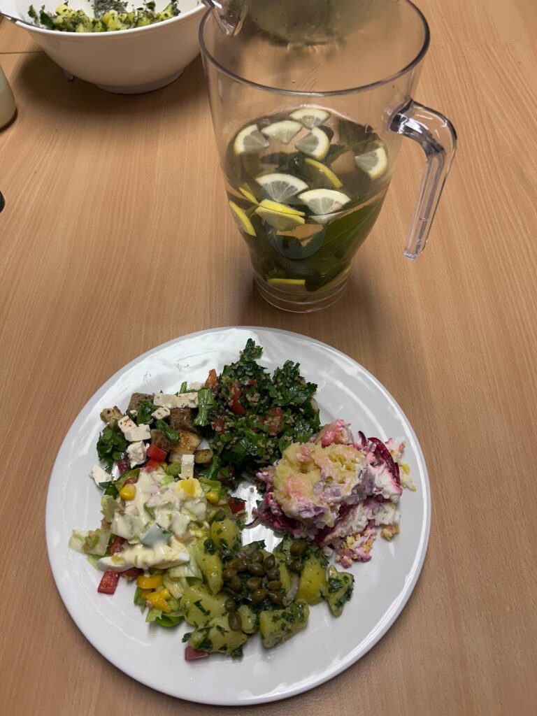Alles nur Salat: Teller mit verschiedenen Salaten, dahinter eine Karaffe mit Zitronenwasser